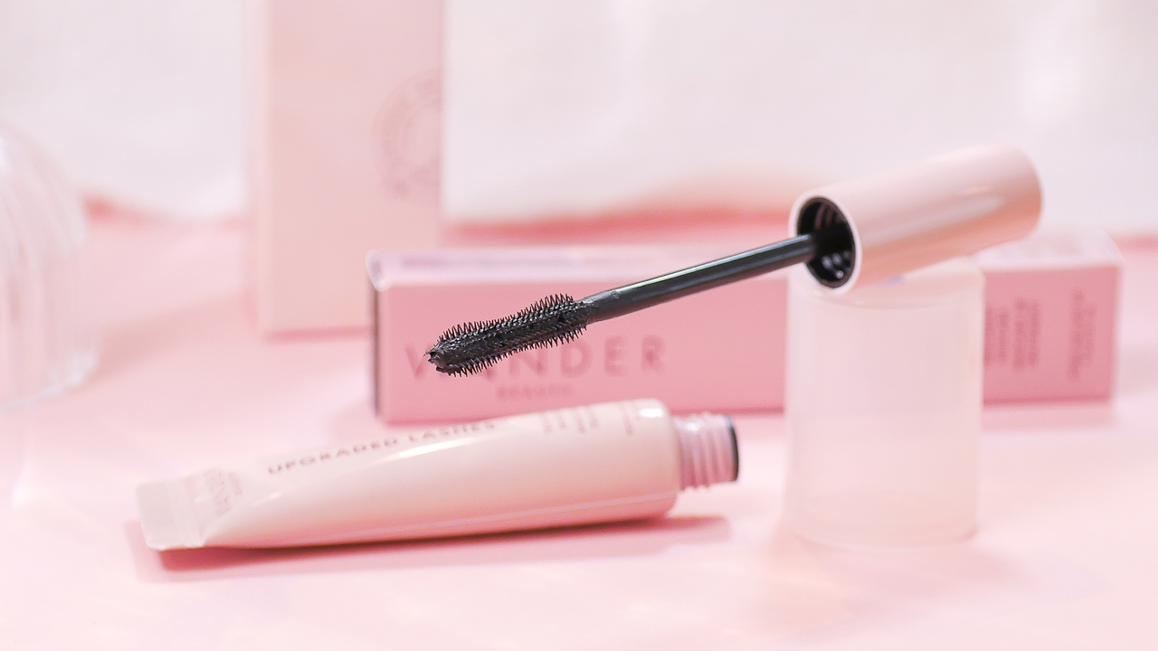 Close-up of a pink mascara tube with brush on a soft background, showcasing makeup details.